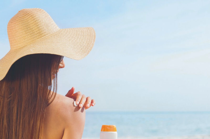 woman applying sunscreen on beach